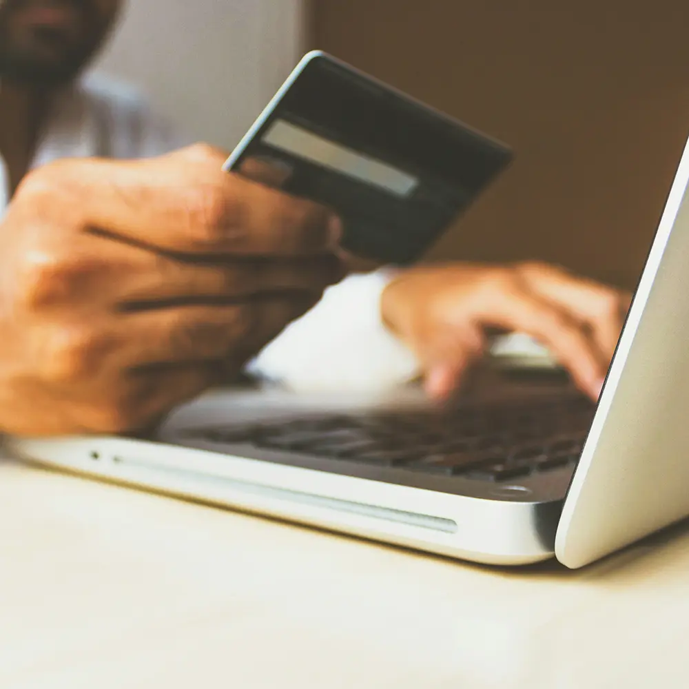 Hands holding a credit card and using a laptop – strategies to turn social followers into paying clients.
