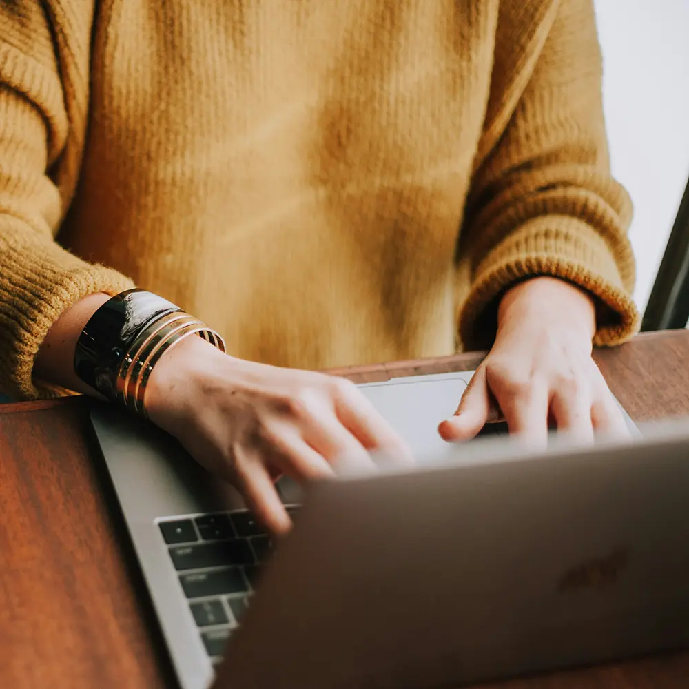Coach typing on a laptop – comparing the best online platforms for fitness coaches.